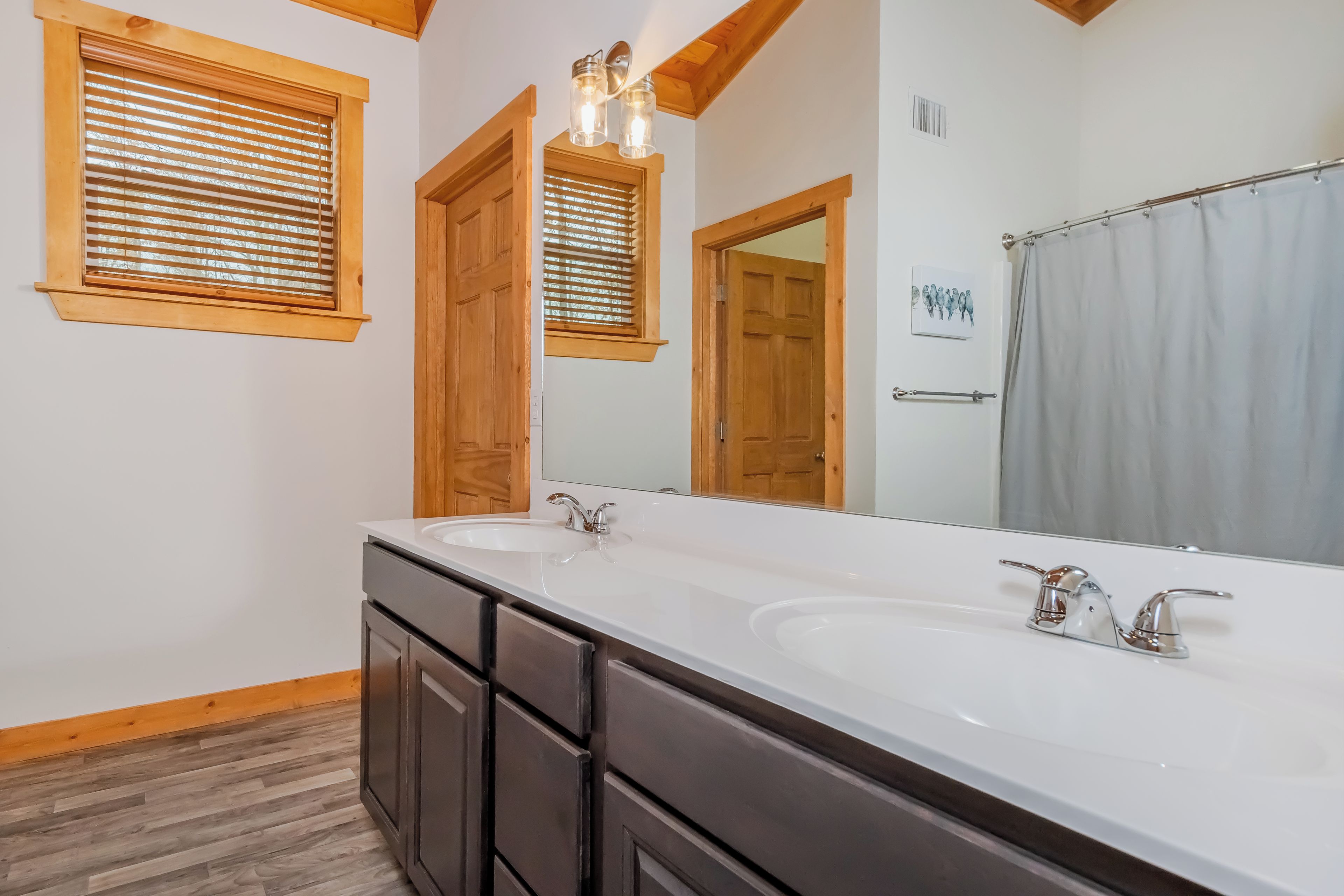 A bathroom with two sinks, wooden cabinets, and a large mirror.