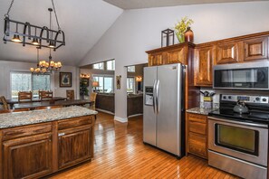 A spacious kitchen with wooden cabinets, a stainless steel refrigerator, a microwave, and an oven.