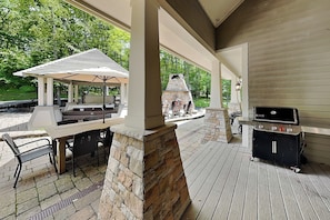Eine Terrasse im Freien mit Grill, überdachter Sitzgelegenheit und Steinpfeiler.