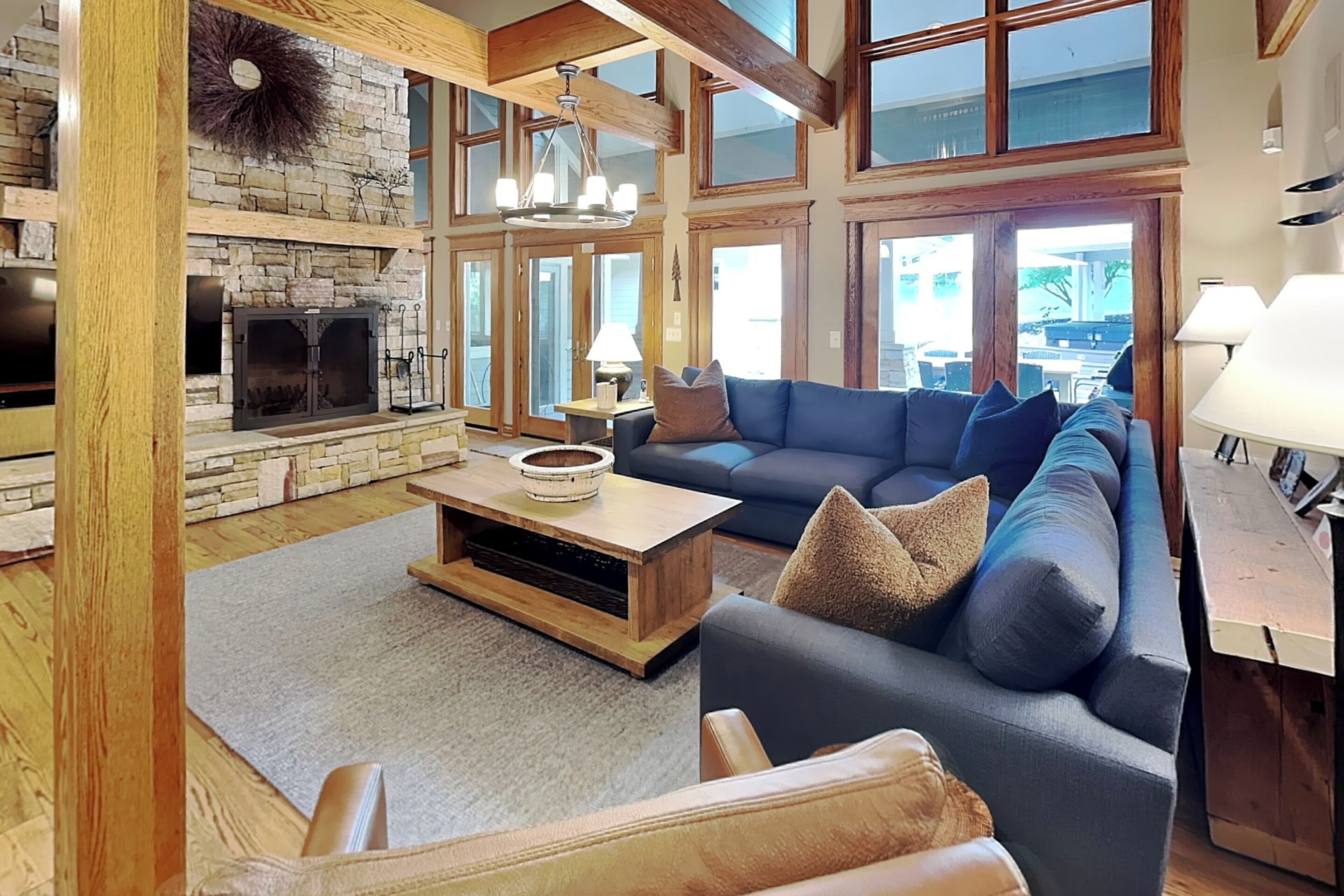 A spacious living room with a stone fireplace, a large sofa, and a wooden coffee table.