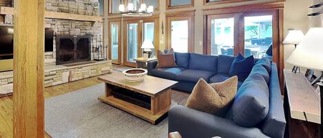 A spacious living room with a stone fireplace, a large sofa, and a wooden coffee table.