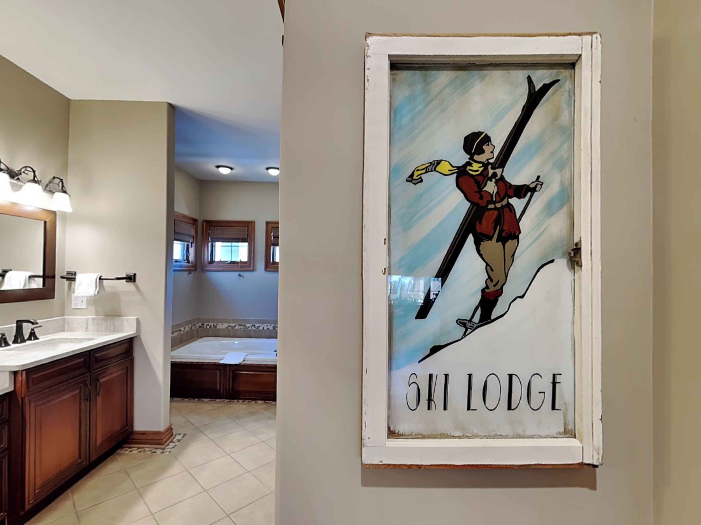Ein Badezimmer mit Waschbecken, Spiegel und einem gerahmten Bild eines Skifahrers an der Wand.