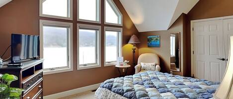 Un dormitorio con una cama grande, televisión, cómoda y ventana con vistas.