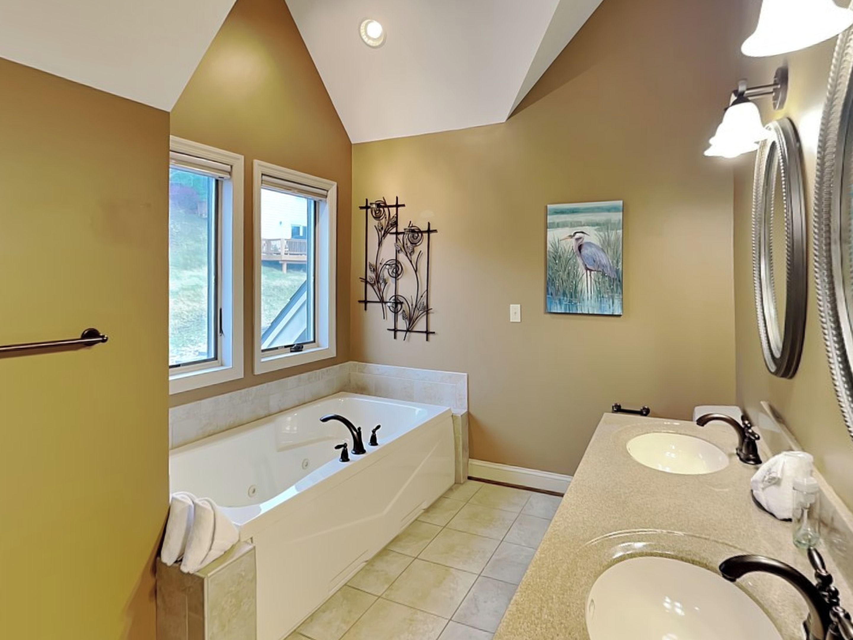 Une salle de bain avec une grande baignoire, deux lavabos et une fenêtre.