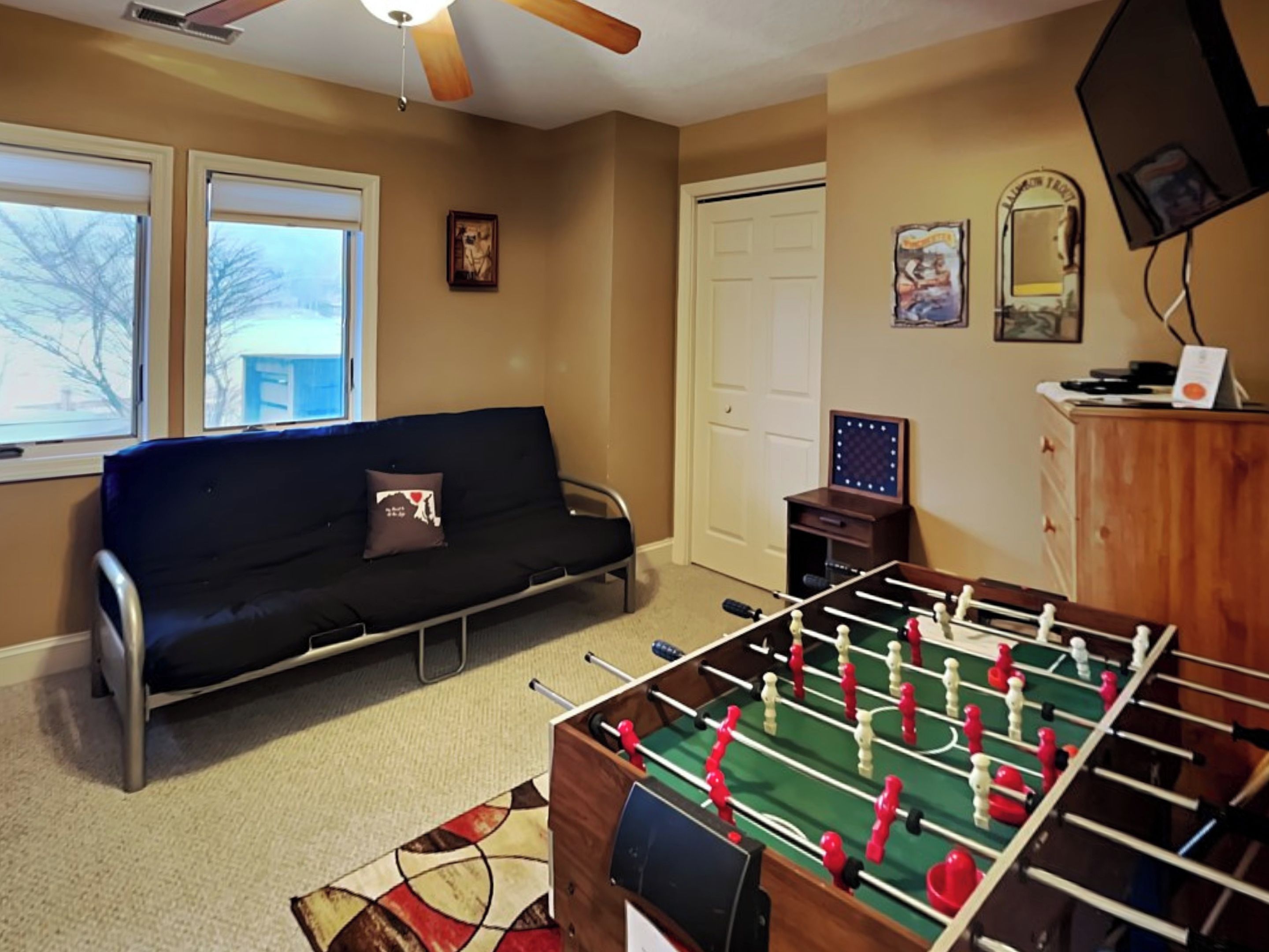A room with a sofa, a foosball table, a television, and a door.