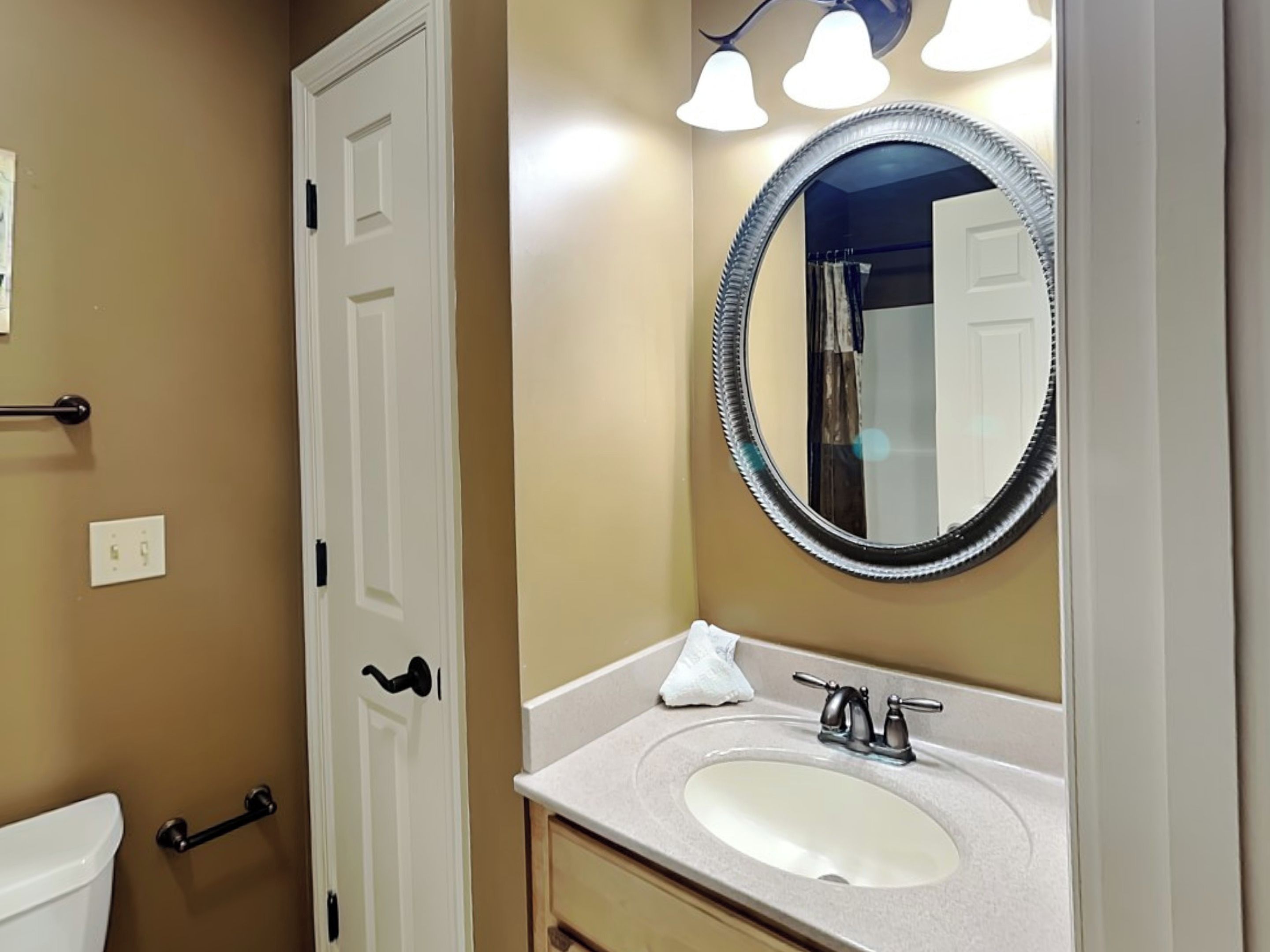 A bathroom with a white sink, a round mirror with a black frame, and a towel on the counter.