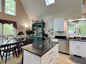 A kitchen with a dining table, chairs, a cabinet, and a window. - Summer Haven by Taylor Made Deep Creek (Oakland)