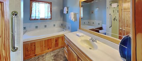 Ein Badezimmer mit Badewanne, Waschbecken, Holzschränken, einem Spiegel und einem Fenster mit Vorhängen.