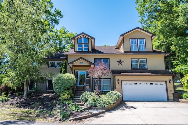 A two-story house with a garage, a front porch, and a well-maintained garden.
