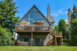 A two-story house with a stone foundation, a balcony with wooden railings, and two umbrellas.