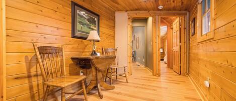 Un interior de madera con una zona de comedor, un cuadro en la pared y un pasillo que conduce a otra habitación.