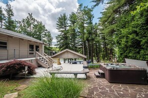 A hot tub, deck, and a small cabin in a wooded area. - Swan's Nest by Taylor Made Deep Creek (Swanton)