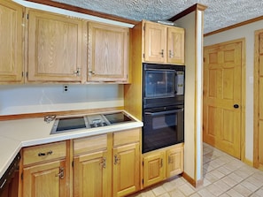 A kitchen with wooden cabinets, a built-in microwave, and an oven. - Swan's Nest by Taylor Made Deep Creek (Swanton)