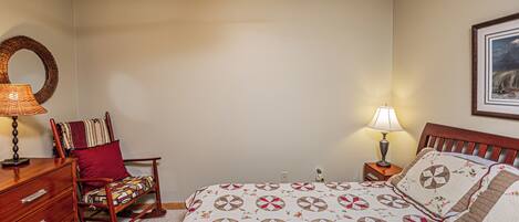 A bedroom with a bed, a rocking chair, a dresser, and two bedside lamps.