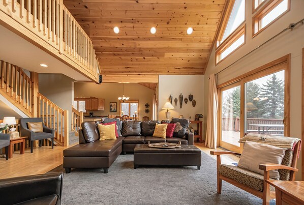 Amplia sala de estar con una escalera de madera, un sofá modular y un ventanal con vistas al exterior.