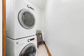 A laundry room with stacked washer and dryer units. - The Haven by Taylor Made Deep Creek (Oakland)