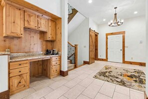 A kitchen with wooden cabinets, a granite countertop, and a chandelier.