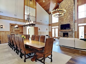 Amplia sala de estar con una gran mesa de comedor de madera, sillas de cuero, chimenea de piedra y pared de piedra.