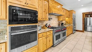 A kitchen with wooden cabinets, a built-in oven, a stove, and a refrigerator. - The Haven by Taylor Made Deep Creek (Oakland)