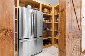A kitchen with a stainless steel refrigerator, wooden cabinets, and a built-in oven. - The Haven by Taylor Made Deep Creek (Oakland)