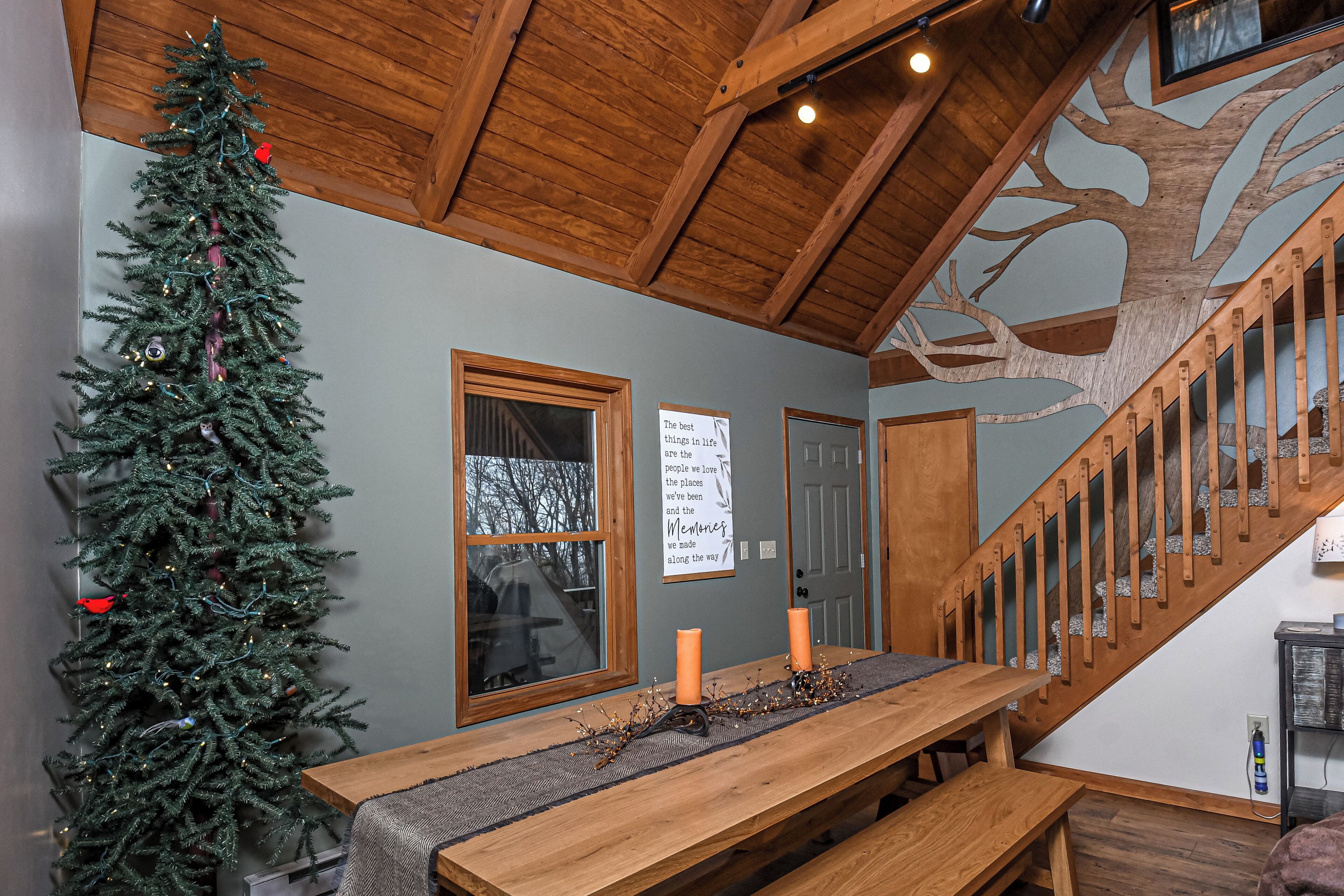 A wooden staircase with a tree mural, a Christmas tree, and a table with candles.