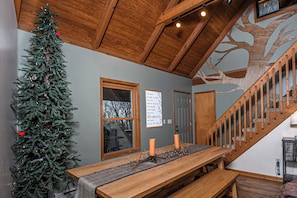 A wooden staircase with a tree mural, a Christmas tree, and a table with candles. - The Perch by Taylor Made Deep Creek (Oakland)