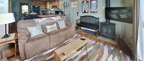 A cozy living room with a sofa, a wooden coffee table, a TV, and a fireplace.