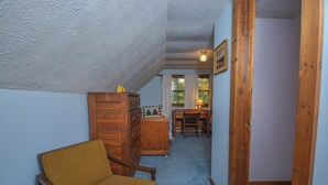 Un couloir étroit avec une chaise en bois, un meuble en bois et un coin repas comprenant une table et des chaises.
