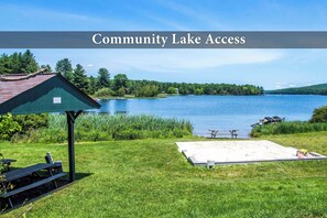 A lakeside picnic area with a covered shelter, picnic tables, and a sandy beach. - The Quarterdeck by Taylor Made Deep Creek (Oakland)