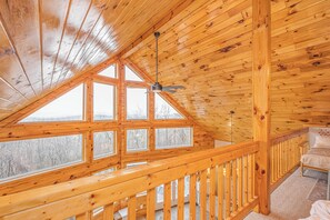 Un intérieur en bois avec un plafond incliné, de grandes fenêtres et une balustrade de balcon.