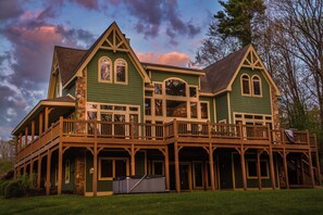 A large, green, two-story house with a balcony and a covered porch. - Unforgettable by Taylor Made Deep Creek (Swanton)