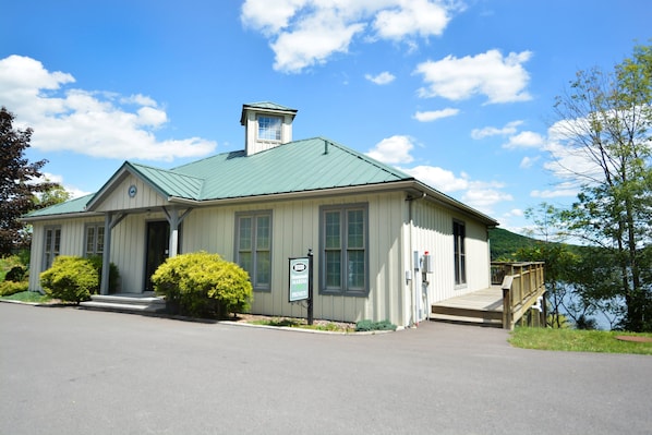 A two-story building with a green roof, a covered porch, and a small tower-like structure on the roof.