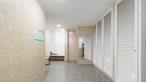 A hallway with a marble floor, a bench, and a door leading to a room with a plant. - OK Las Canteras 5C by CanariasGetaway (Las Palmas de Gran Canaria)