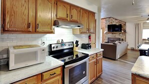 A kitchen with wooden cabinets, a microwave, a stove, and a stone wall in the background.
