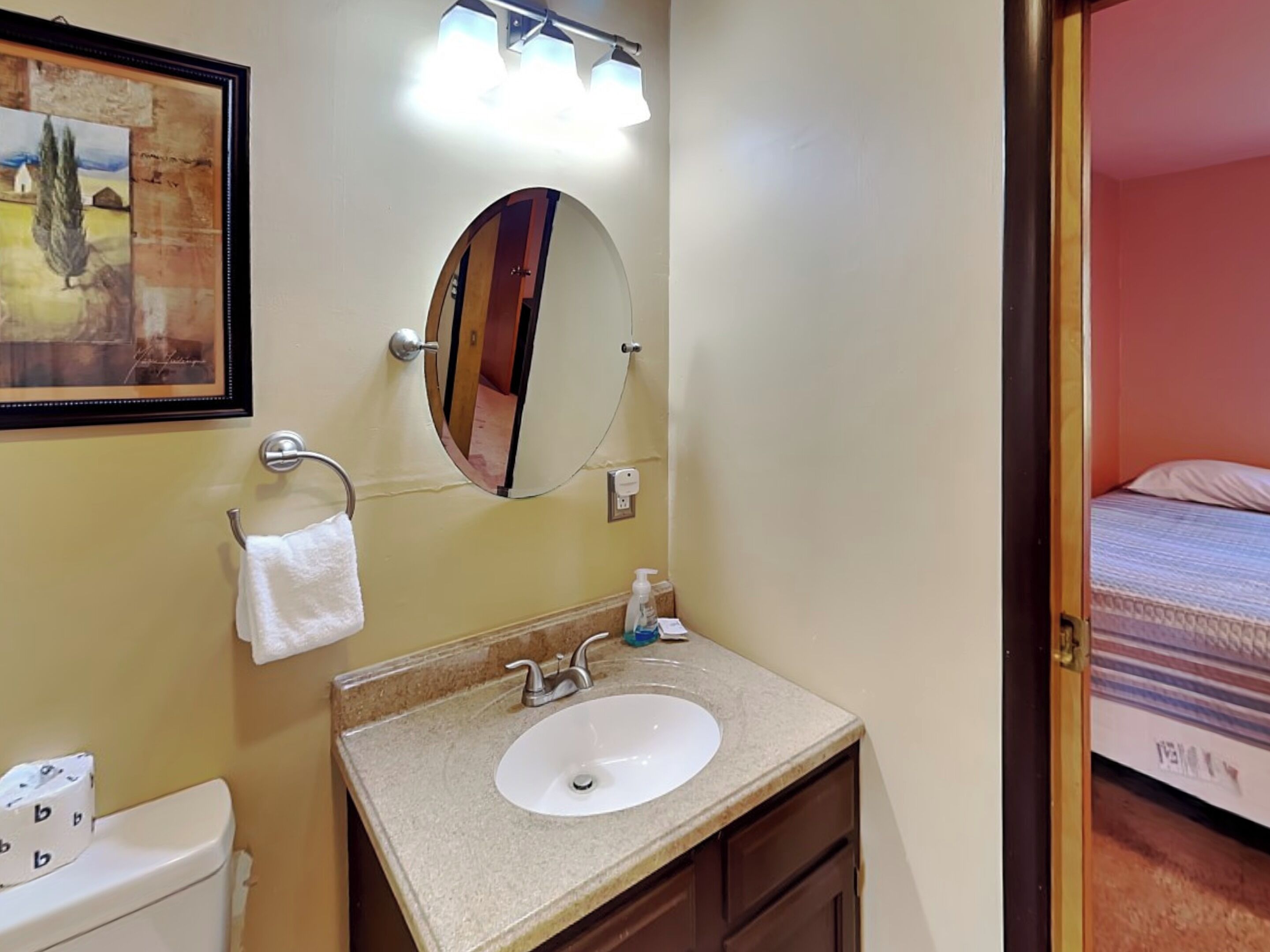 A hotel bathroom with a sink, mirror, and towel rack.