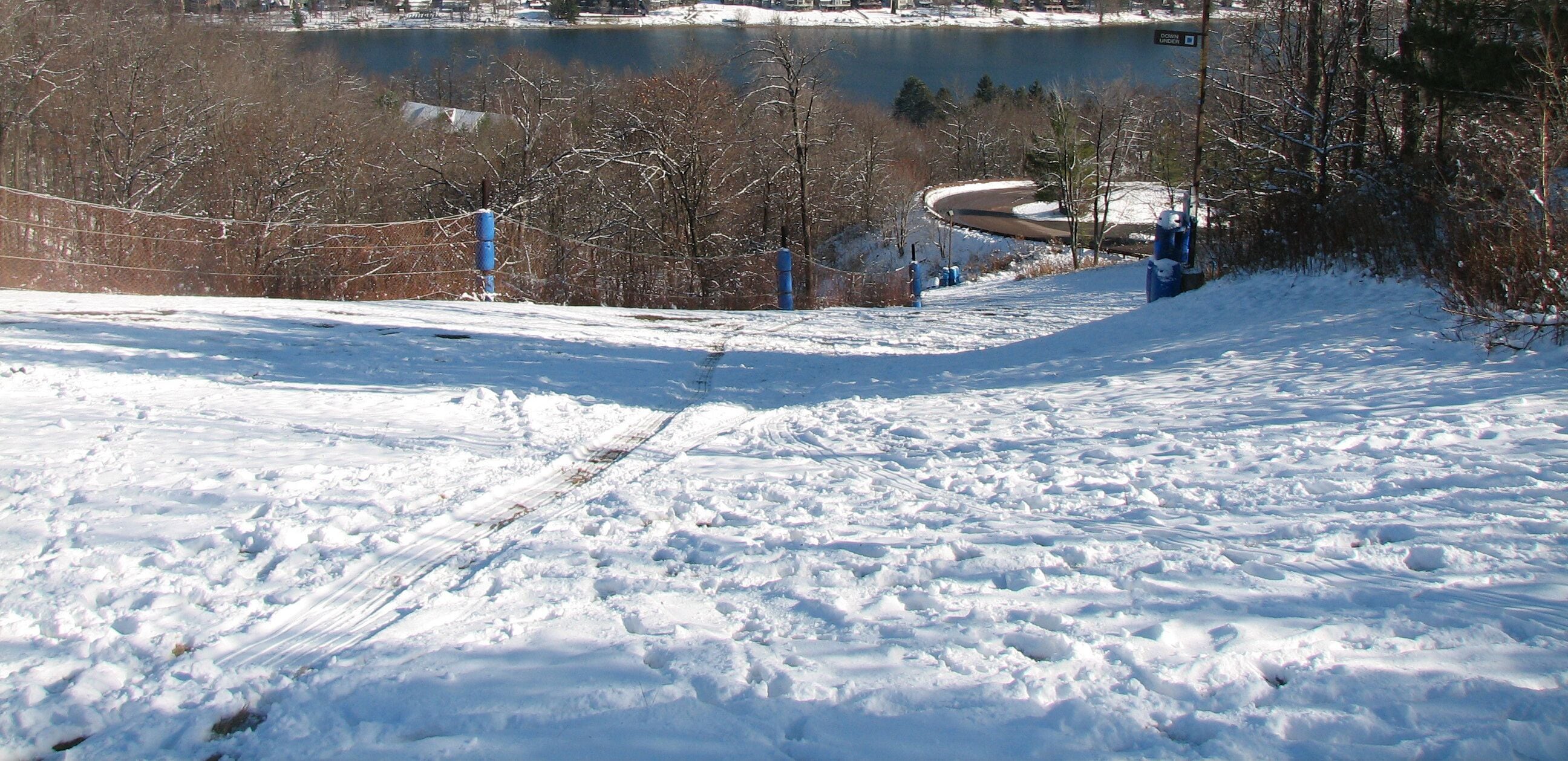 A snowy ski slope with a clear view of a lake and a town in the background.