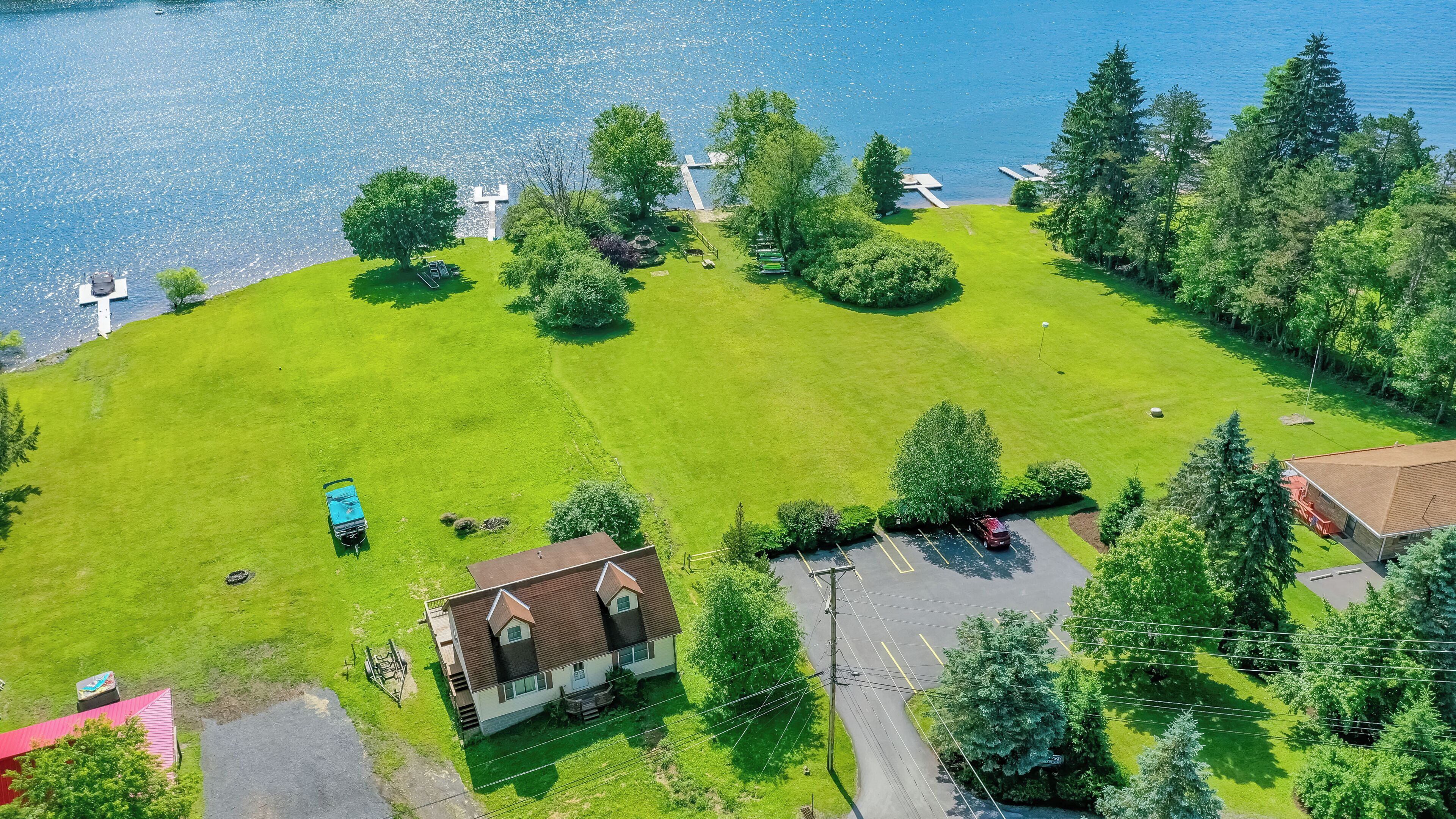 An aerial view of a property with a large grassy area, a small building, and a dock extending into a body of water.