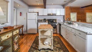 A kitchen with white cabinets, a wooden countertop, a stove, and a sink. - Pivots & Divots by Taylor Made Deep Creek (McHenry)