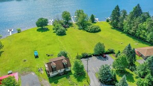 An aerial view of a property with a large grassy area, a small building, and a dock extending into a body of water. - Pivots & Divots by Taylor Made Deep Creek (McHenry)