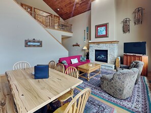 A spacious living room with a wooden staircase, a fireplace, a red sofa, and a television. - Vista Emmanuel by Taylor Made Deep Creek (McHenry)