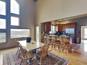 A spacious kitchen with wooden cabinets, a large island, and a dining area with a wooden table and chairs. - Vista Emmanuel by Taylor Made Deep Creek (McHenry)