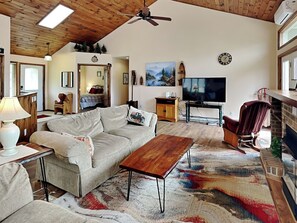 A living room with a sofa, coffee table, TV, and fireplace. - Wake at the Lake by Taylor Made Deep Creek (Swanton)