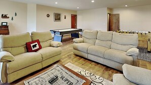 Una sala de estar con dos sofás, mesa de billar y mesa de futbolín.