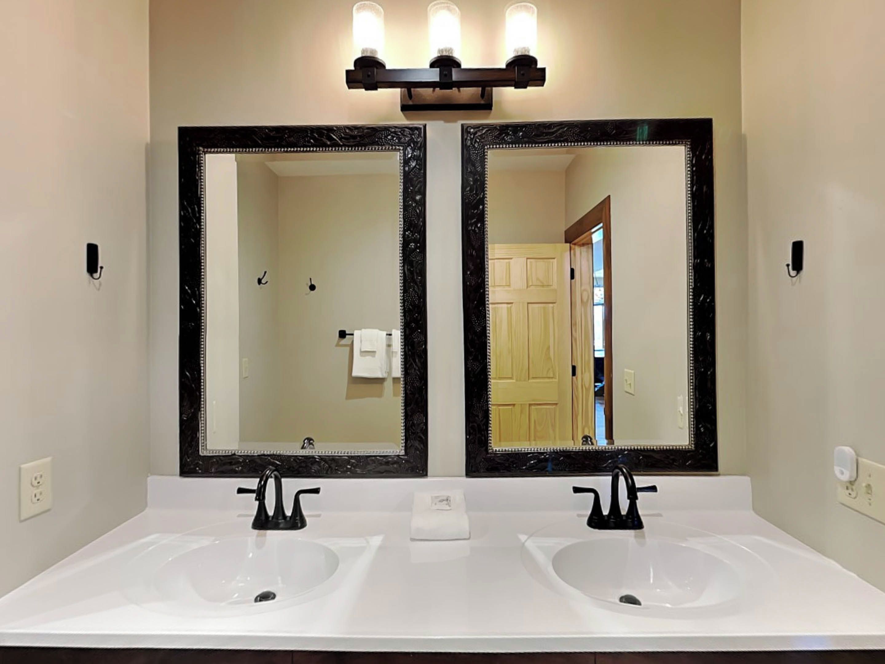 A bathroom with two sinks, a large mirror, and a light fixture above.