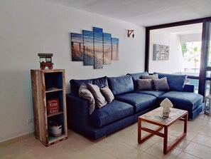 Un salon avec un canapé bleu, une table basse en bois et une bibliothèque.