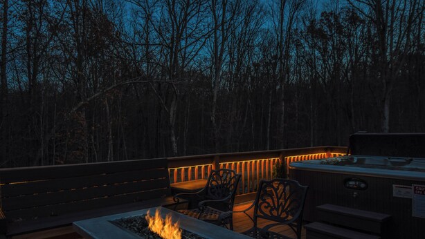 An outdoor deck with a fire feature, seating, and a hot tub. - Wine Down by Taylor Made Deep Creek (Oakland)