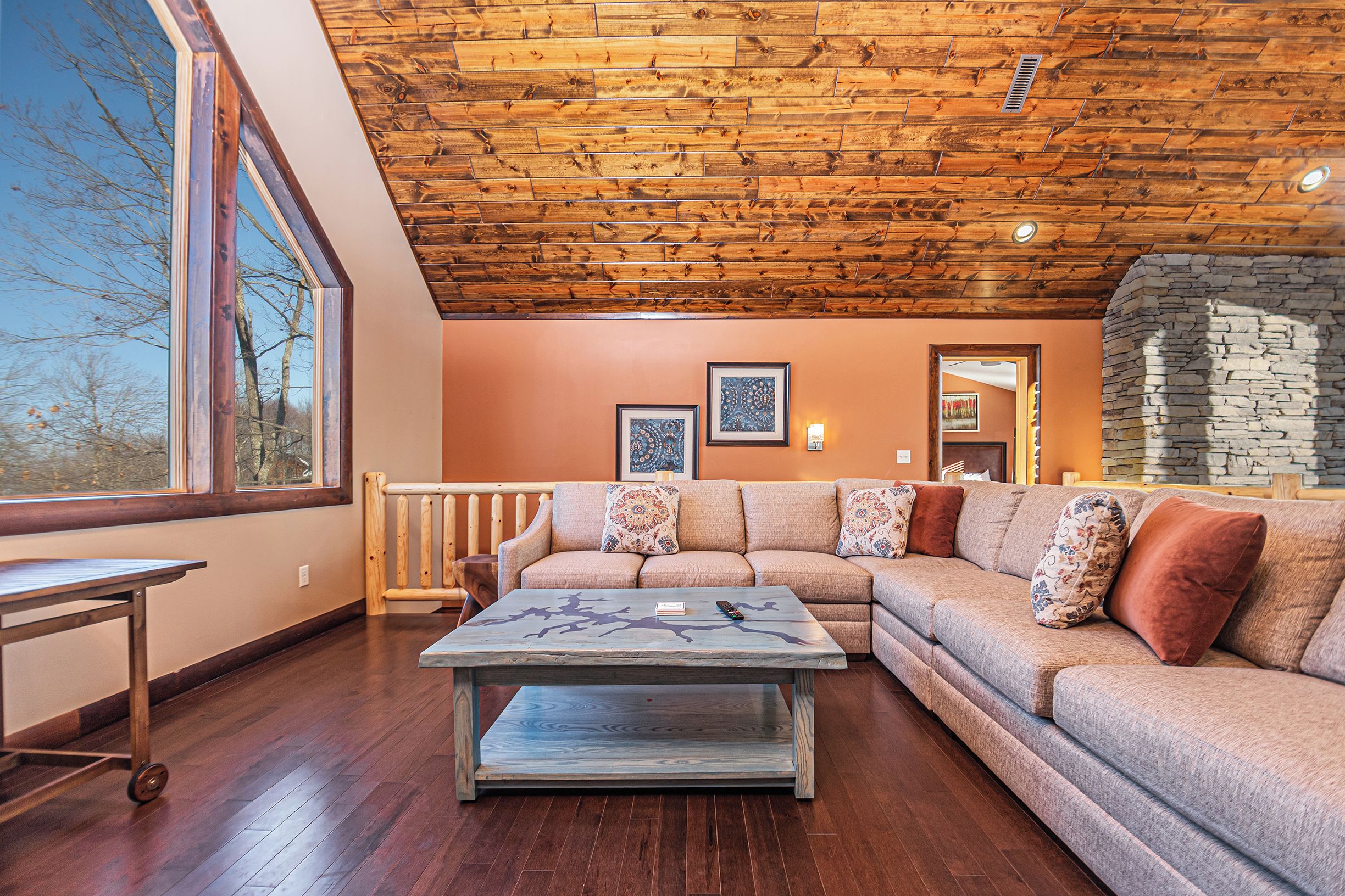 Una sala de estar acogedora con techo de madera, un ventanal grande, un sofá modular y una mesita de centro.