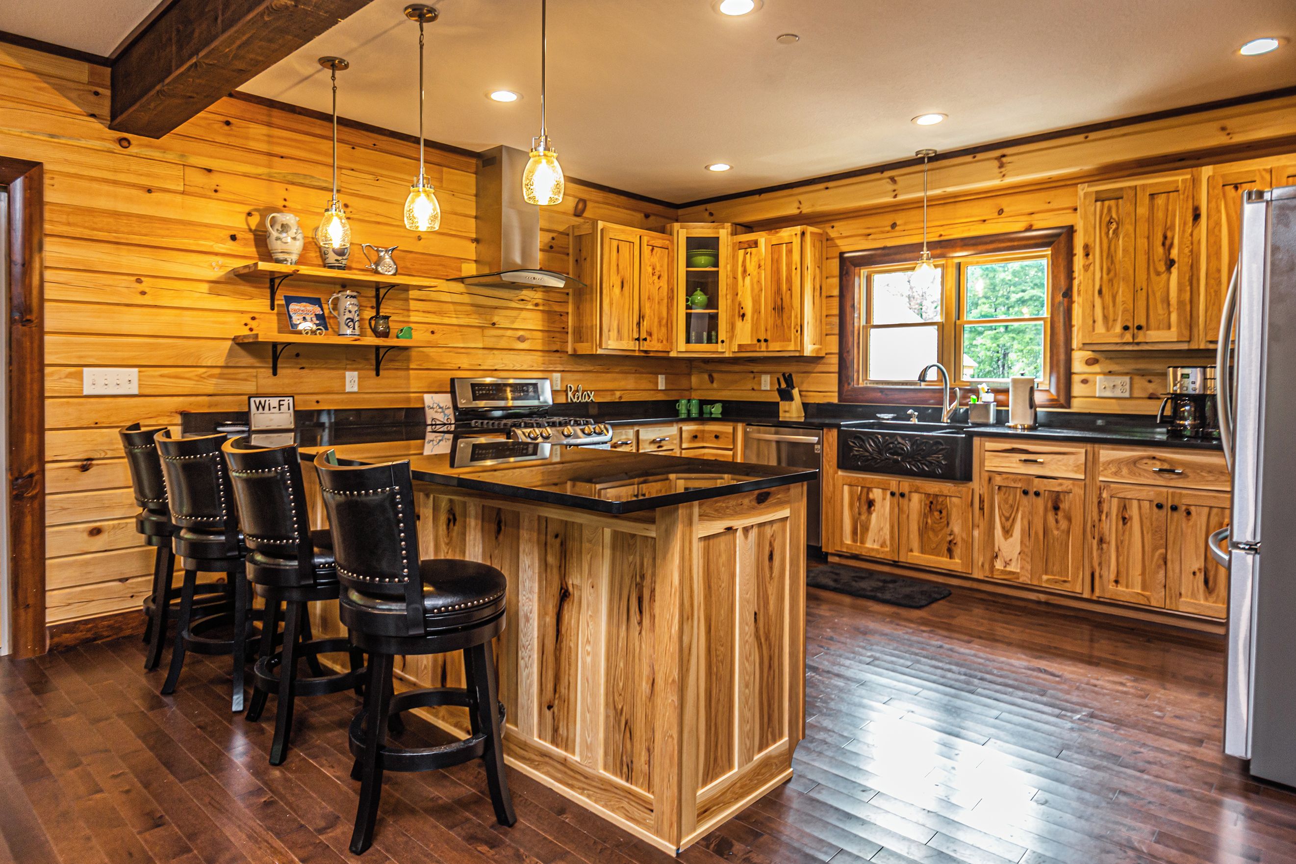 A spacious kitchen with wooden cabinets, a central island, and bar stools.