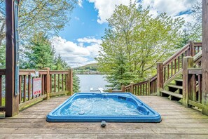 A wooden deck with a hot tub overlooking a lake. - Wisp N Around by Taylor Made Deep Creek (McHenry)
