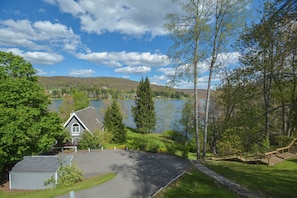 En ejendom ved søen med en indkørsel til et hus, omgivet af træer og en klar søudsigt.
